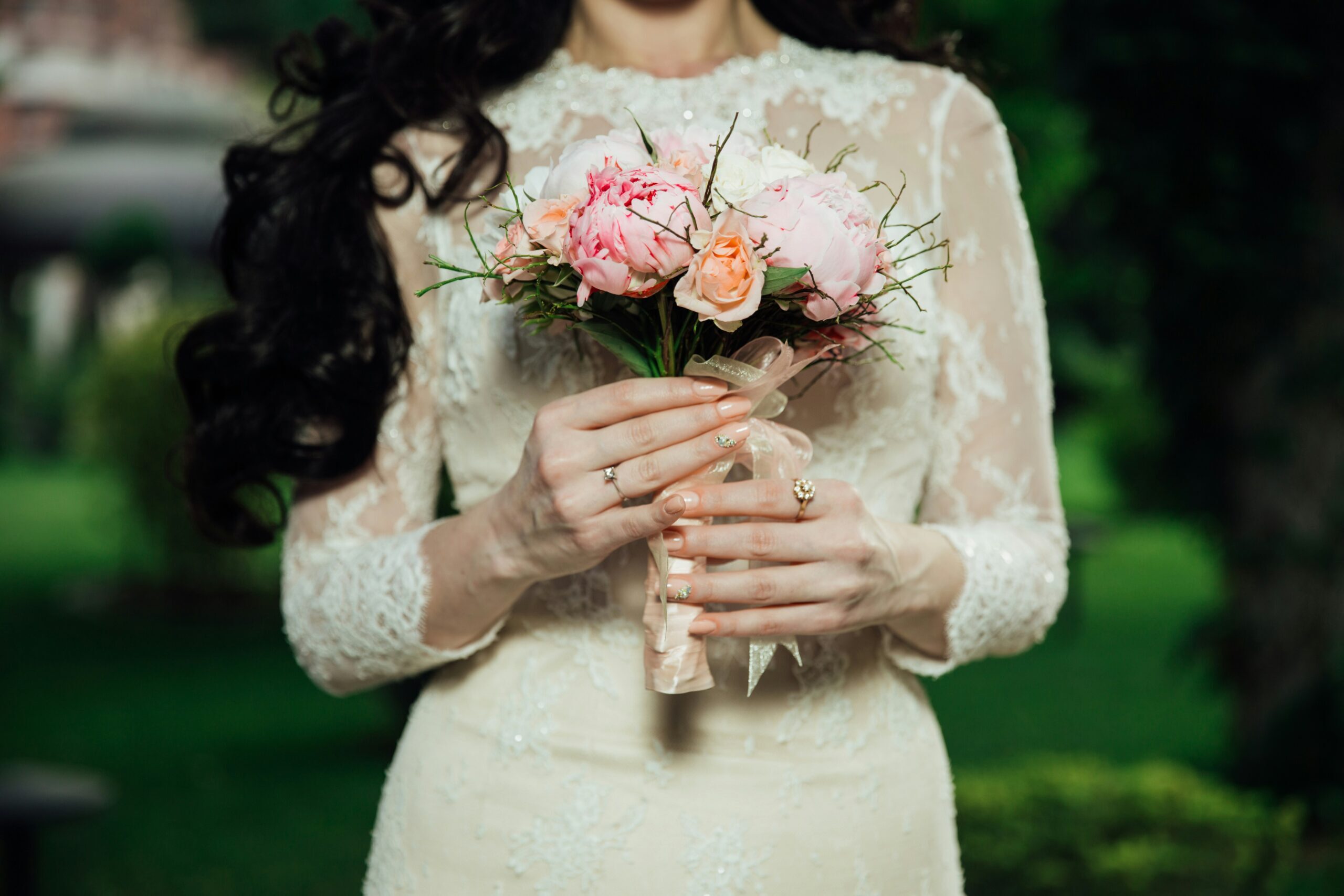 A person wearing a white wedding dress, holding a brides bouquet.