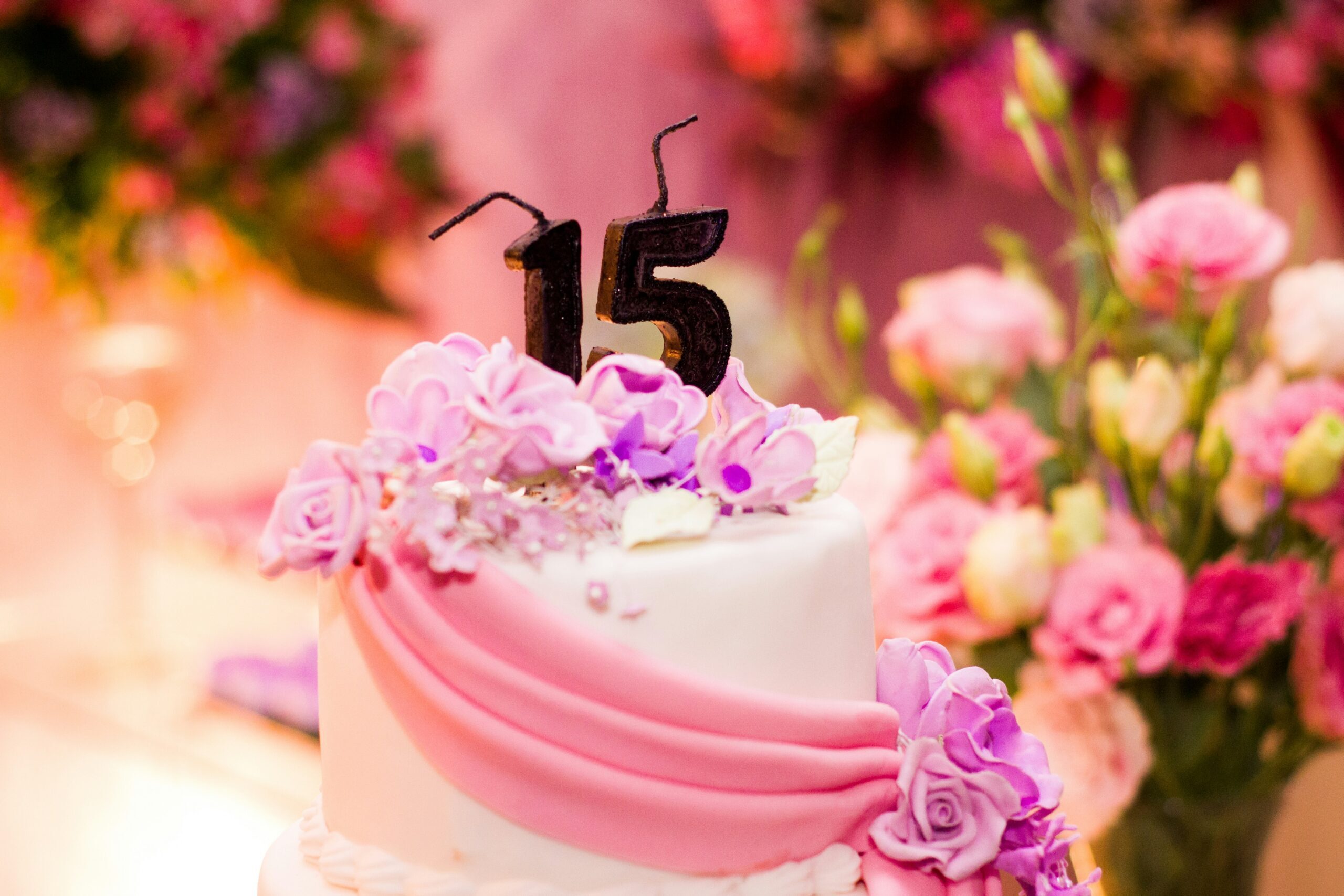 A pink birthday cake with a colourful birthday decoration.